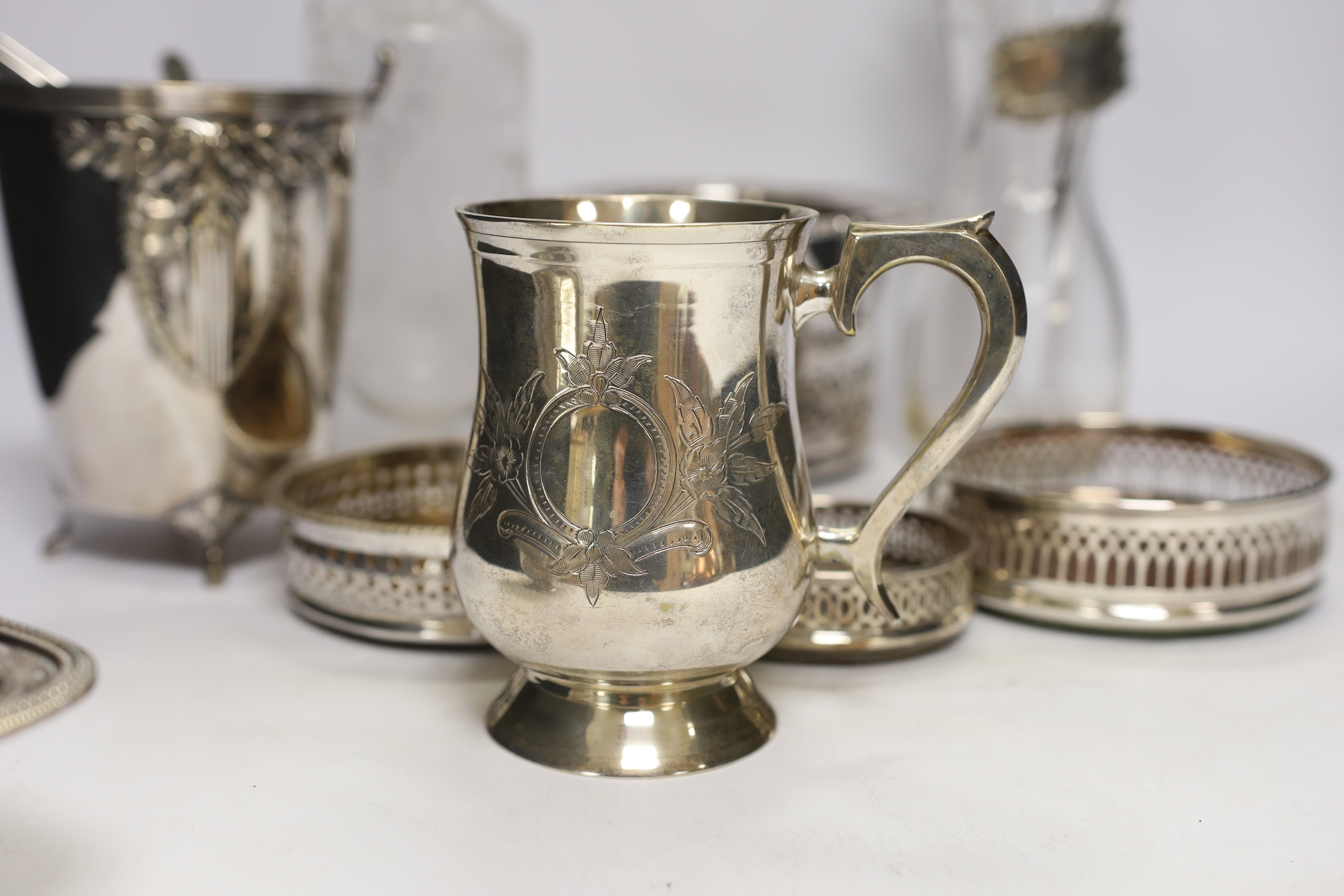Two decanters; one with silver mount and one with etched body, together four wine coasters, a bucket raised on four feet, etc.